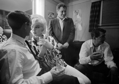 Lawrence Schiller, Marilyn Monroe and Wally Cox, with Dean Martin in the background, celebrating her birthday on June 1, 1962 in Dean Martin's dressing room on the set of "Something's Got To Give", Los Angeles 1962, Galerie Stephen Hoffman, Muenchen
